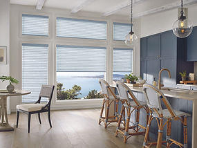 Sonnette roller and solar shades in a kitchen with chairs and blue cabinets.