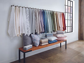 Colourful drapery, upholstery and pillows with patterns on wooden bench.