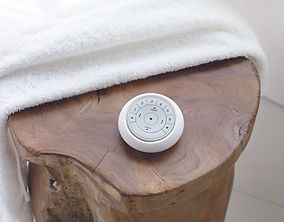Hunter Douglas white pebble remote on a wooden table.