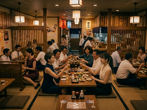 居酒屋の広々としたお座敷で、賑やかに暑気払いの宴会を楽しむ大人数のグループ。ビールや料理を囲み、笑顔で談笑しているアットホームな宴会の風景。