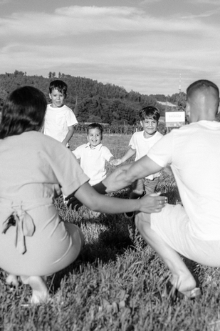 Eltern knien mit offenen Armen, drei lachende Kinder rennen auf sie zu – Familienshooting voller Freude.