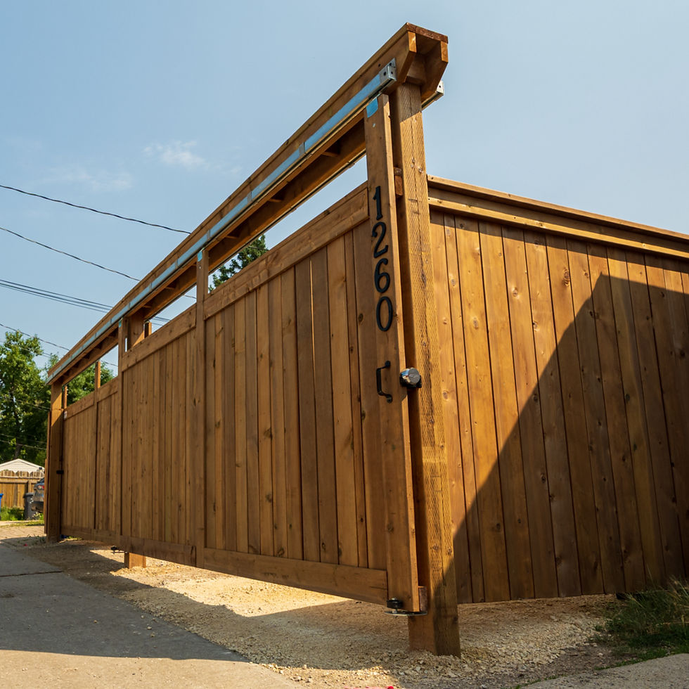 Tall wooden privacy gate with house number 1260 in a sunny alley, against a clear blue sky.