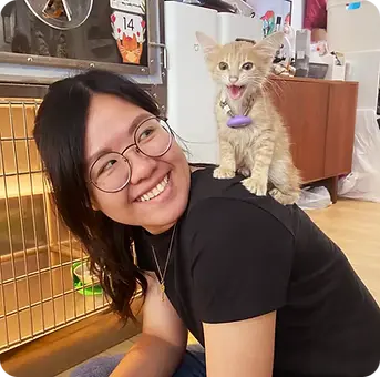 A lady with a kitten on her shoulder.