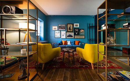 Lobby with bookshelves along the sitting area featuring pair of yellow chairs, blue couch, & artwork