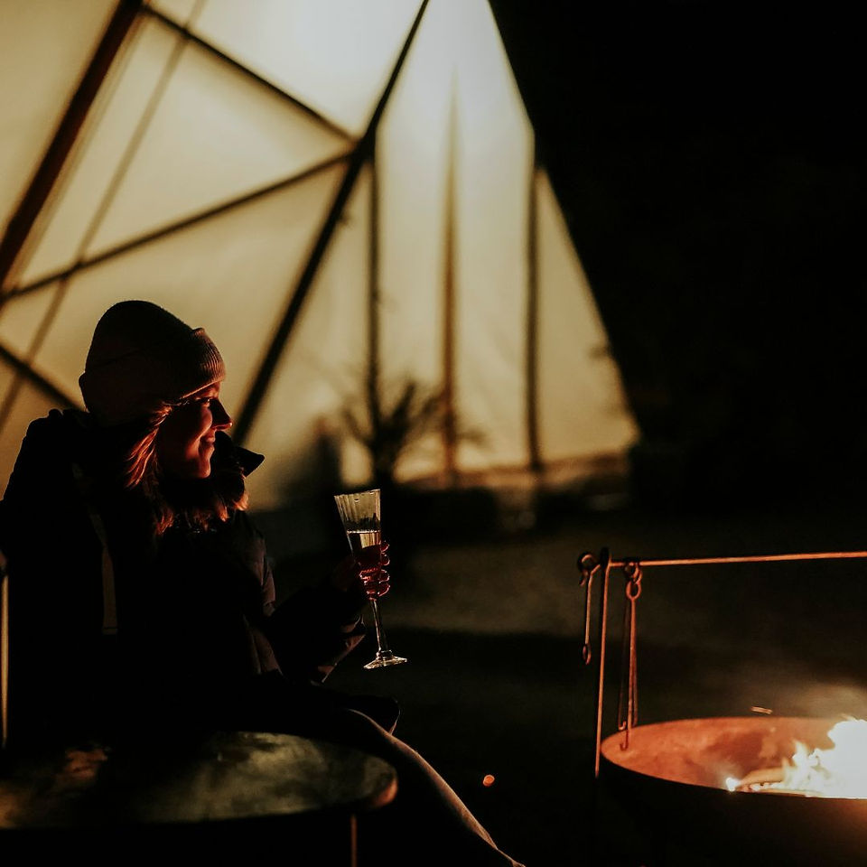 Tipi glamping woman champagne by the fire