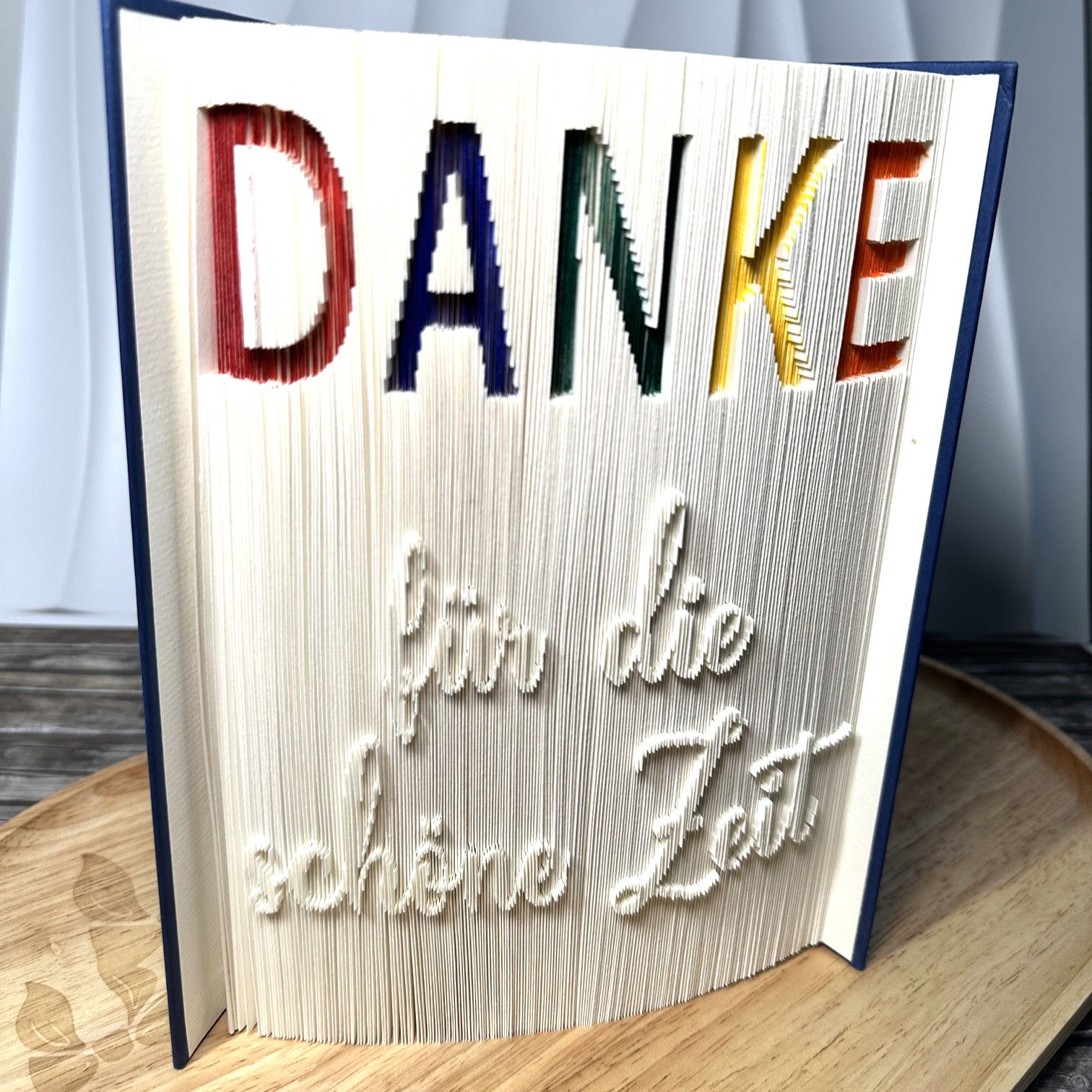 Handgefertigte Buchfaltkunst als Abschiedsgeschenk für Lehrer und Pädagogen mit farbigem Danke-Schriftzug zum Schulabschluss.