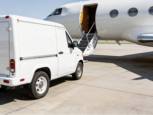 Catering delivery truck parked in front of private jet stairs 