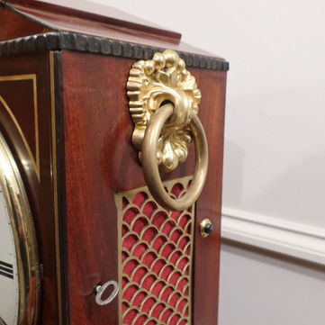 Antique English Regency mahogany small bracket clock with architectural shaped top and brass string inlay detail to the front by Thomas Connold striking the hours on a bell. The clock stands on a wall bracket