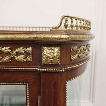 an early 20th century antique French style mahogany display cabinet with bow ends and glass doors adorned with bronze gilt ormolu mounts