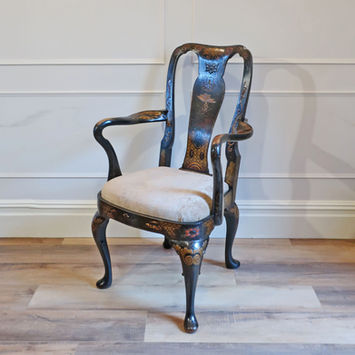 an antique Georgian black lacquered antique armchair in the Queen Anne style decorated in chinoiserie design with flowers, pagodas, dragons and tree hand painted detail with shaped arms standing on cabriole legs