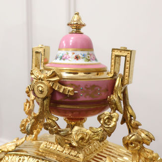 A French decorative bronze gilt antique mantel clock with porcelain panels. The eight day movement by Japy Freres strikes the hours on a bell