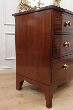 an antique Georgian mahogany bow fronted small chest of drawers with wooden and brass knobs standing on splayed feet with ebony string inlay