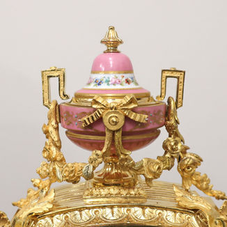 A French decorative bronze gilt antique mantel clock with porcelain panels. The eight day movement by Japy Freres strikes the hours on a bell