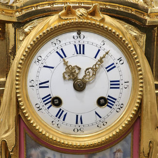 A French decorative bronze gilt antique mantel clock with porcelain panels. The eight day movement by Japy Freres strikes the hours on a bell