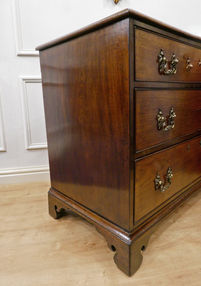 A small Georgian mahogany chest of drawers from the Chippendale period with Rococo style brass handles standing on shaped bracket feet