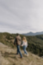 Couple holding hands walking up a grassy hill
