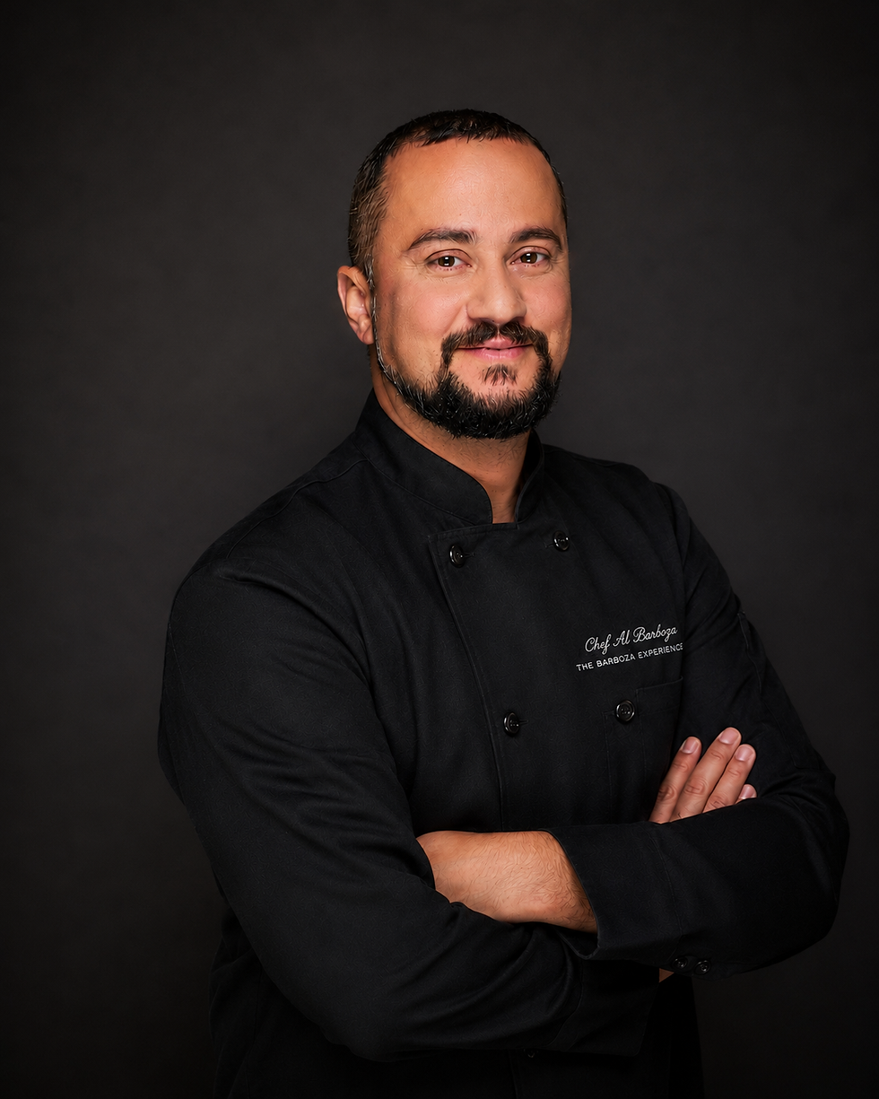Chef Al Barboza in a black chef coat, photographed against a dark studio background for The Barboza Experience.