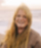 Woman with long blonde hair smiling at the camera on a beach