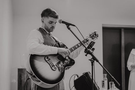 Sam Sheridan, professional wedding musician, performing at a wedding while wearing a suit, stepping away from the microphone.