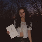 author profile photo, infront of trees holding book