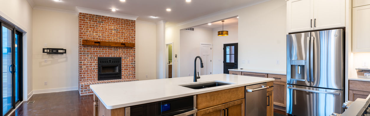 Modern kitchen with island and brick fireplace.