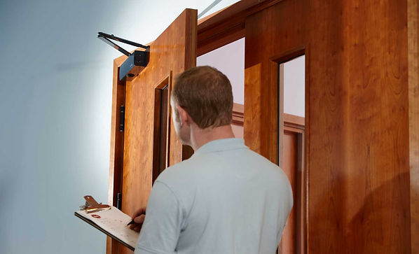 Man with clipboard, inspecting a fire door