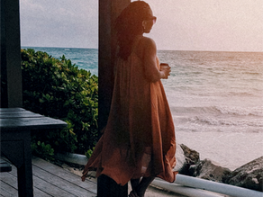faded photo of a woman in a floaty dress looking out to the beach