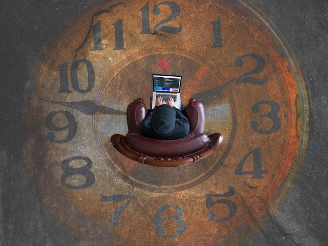 Birdseye view of person on computer with clock face background