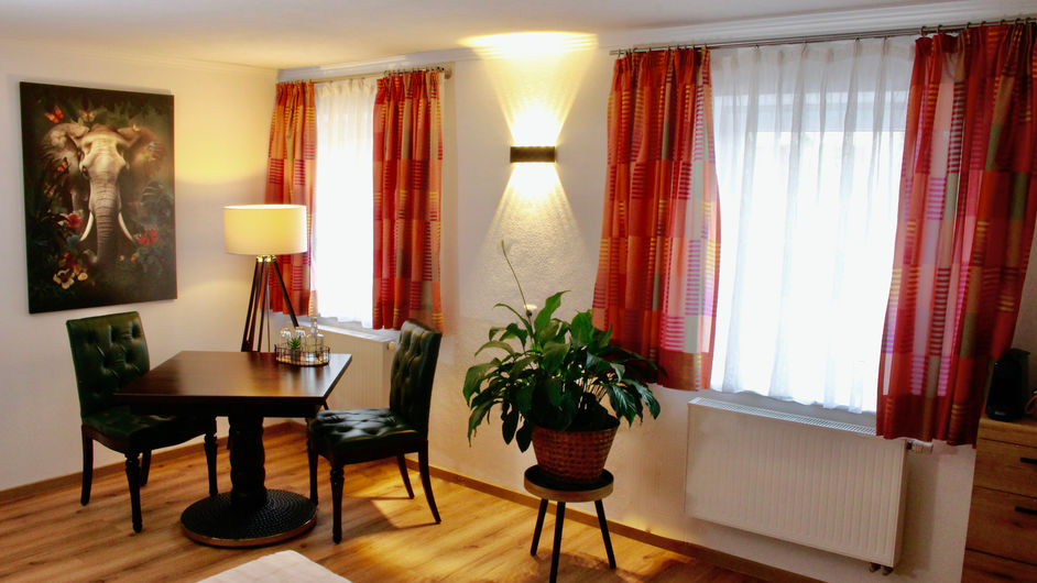 Sitzecke im Elefantenzimmer mit grünen Stühlen, Tisch und Elefantenbild