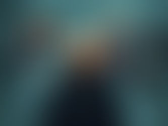 A happy person stands in the foreground while behind them, rendered in a hazy dreamlike style, stand the people in their lives including a spouse, children, grandchildren and coworkers, all smiling, against a smoky gray and teal background with jewel toned accents and a slightly mystical atmosphere.
