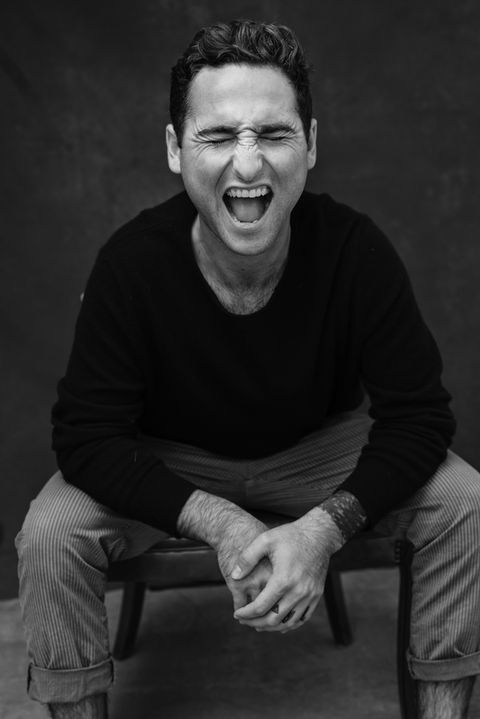 Black and white portrait of a young man with dark hair, mouth open in a joyful scream, capturing raw emotion and youthful energy.