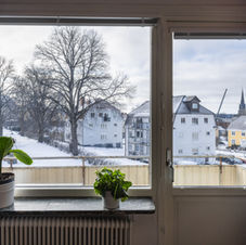 Våning 2: utsikt genom fönstret mot träd och närliggande bostadshus.