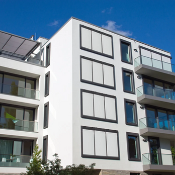 Ljusa screenmarkiser monterade på modern flerbostadsfastighet.