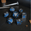 Thumbnail: Black dice set with metallic blue and silver foil and silvler and blue  numbers made with Jesmonite, on a dark background
