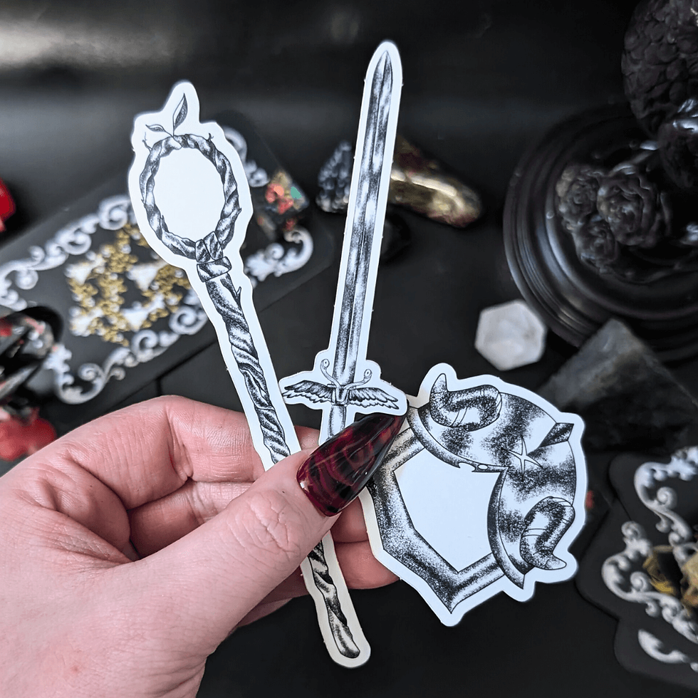 Hand holding stickers of staff, sword, and shield on a dark background.