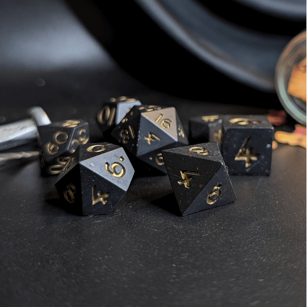 Black dice set with metallic gold numbers and blood splats made with Jesmonite, on a dark background