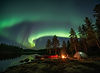 Northern Lights aurora borealis over wilderness canoe camping site in Sweden with red cano