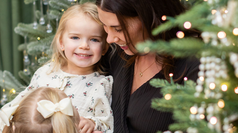 A woman and two smiling children in festive outfits by a decorated Christmas tree at a studio in Guelph, Ontario with lights and ornaments, creating a joyful holiday scene at a studio in Guelph, Ontario.
