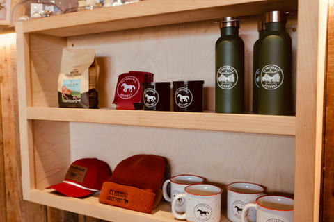 Merchandise display at Clydesdale Creamery featuring hoodies, hats, candles, and Clydesdale Outpost products for sale in downtown Whitefish, Montana