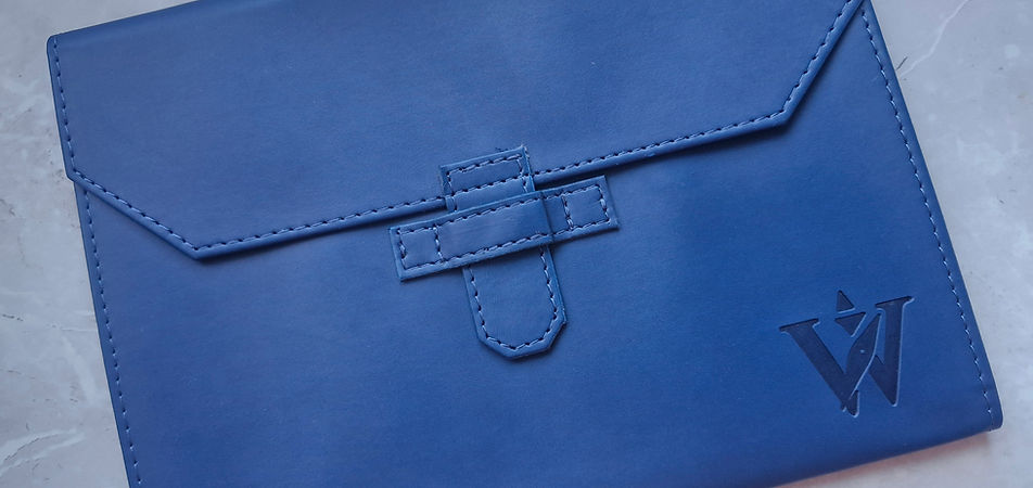 A closed navy blue Newhide A5 document folio featuring the debossed Weedon & Co. logo, resting on a marble surface.