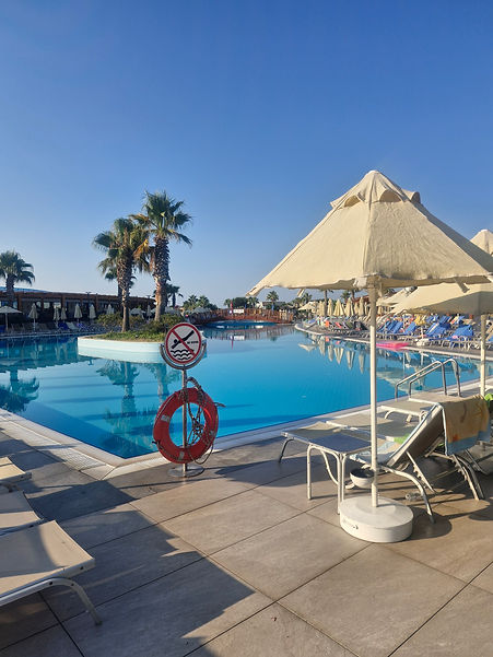 Crystal clear swimming pool area with palm trees and sunbeds at Aquasis De Luxe Resort & Spa, Didim