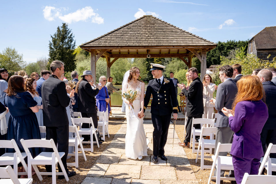 The bride and groom are walking down the isle in a Brookfield barn surrounded by friends and family. 