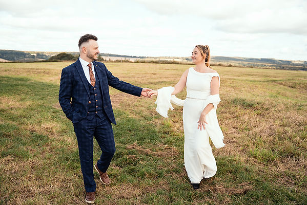 Bride and groom sharing a romantic moment at Halnaker Windmill in West Sussex, with stunning views and the iconic windmill creating a perfect backdrop.