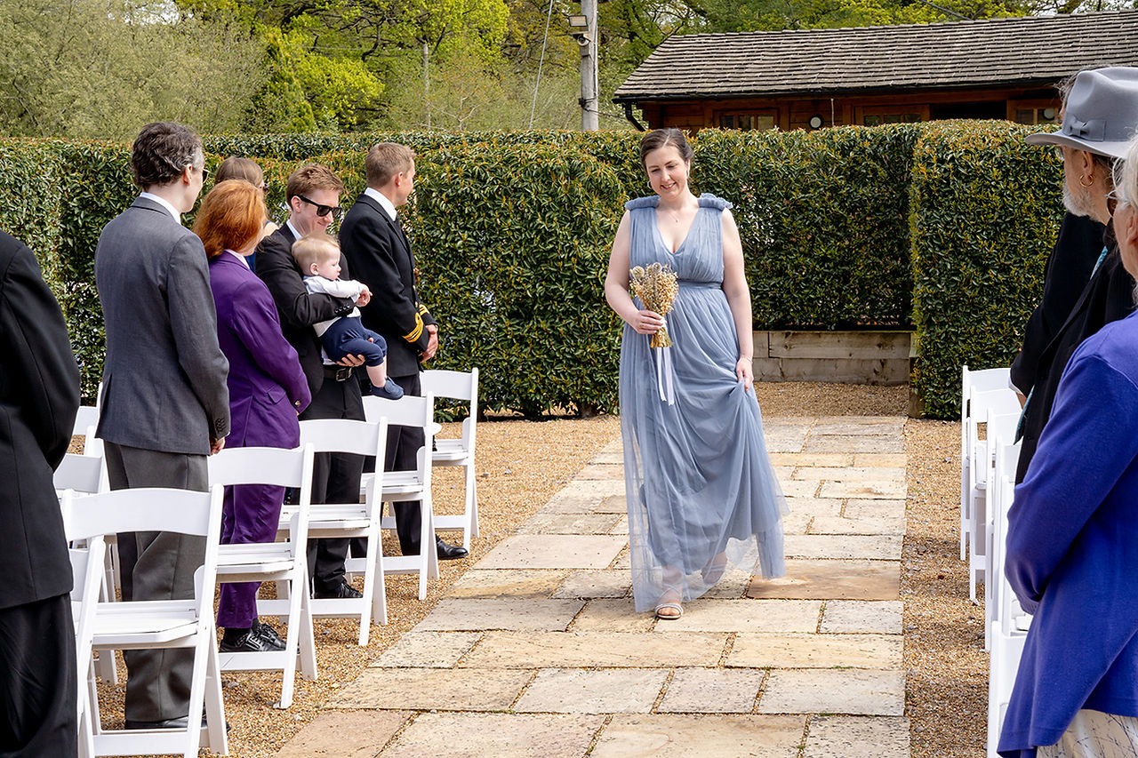 Bridesmaids walking down the aisle at Brookfield Barn, leading the way to the bride with smiles and excitement.