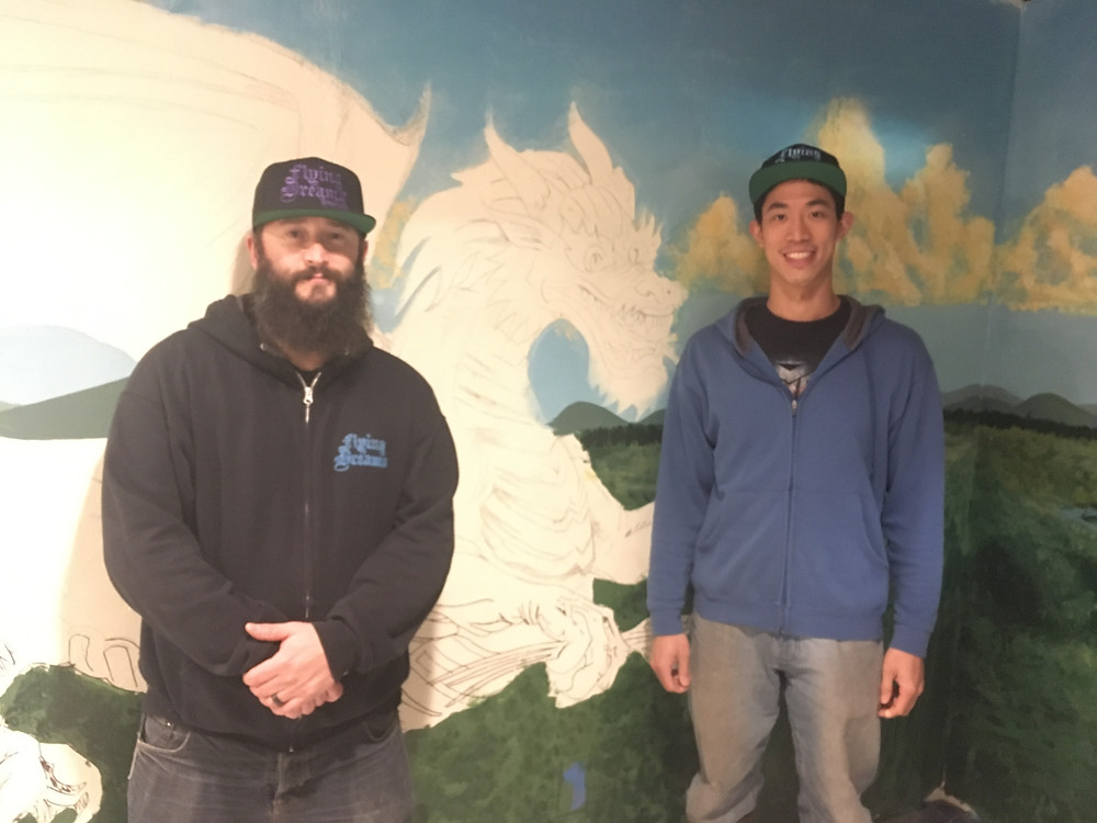 Flying Dreams owner Dave Richardson (left) and Head Brewer Lee Chiang (right) stand in front of a mural painted by artist Kai Griffiths.