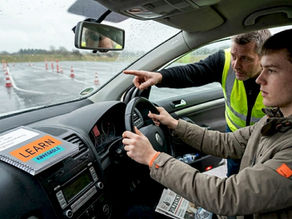 En elev træner køreteknik sammen med sin kørelærer ved bilen.