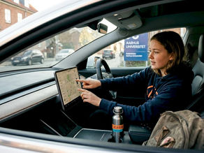 En ung studerende sidder og justerer indstillingerne i en elbil.