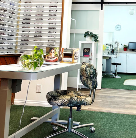 A picture showing a desk with flowers and a wall with spectacles