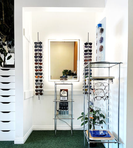 A photo of a big mirror next to two shelves of spectacles