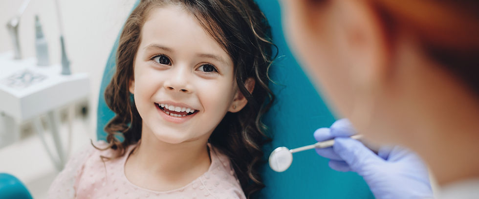Petite fille aux cheveux bouclés regardant et souriant vers le dentiste après un contrôle.